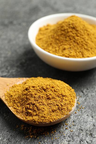 istock Spoon and bowl with dry curry powder on dark textured table, closeup 2246022387
