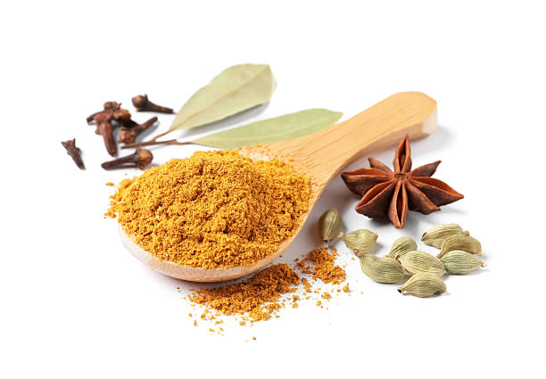 Spoon with dry curry powder and other spices isolated on white
