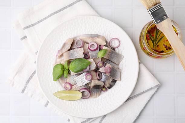 istock Plate with tasty fish, onion and marinade on light tiled table, flat lay 2246027075