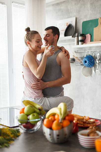istock Romantic couple embracing in a bright kitchen while sharing a cup of coffee at home 2246028327