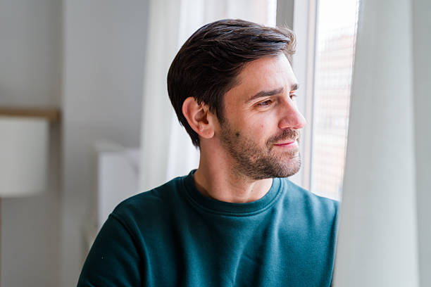 istock Thoughtful man looking out window contemplating future at home 2246029056