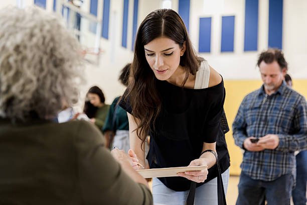 istock Woman signing paperwork at a voting poll or registration event 2246029177