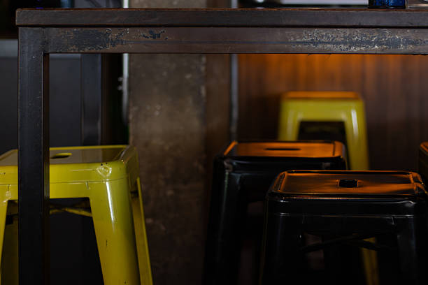 SÃO PAULO, BRAZIL, 7 26 25: A detailed shot of vibrant yellow and sleek black industrial-style metal bar stools positioned beneath a counter in a contemporary cafe setting. The city is home to Avenida Paulista.