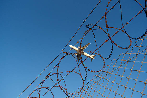 istock Airport barbed wire fence with plane ascending, security concept. 2246032362