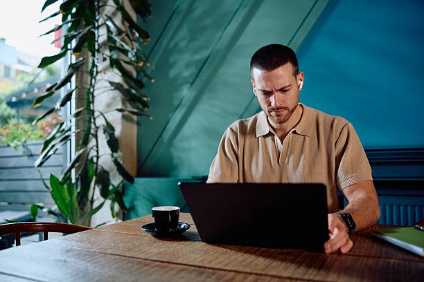 istock Young adult man working remotely at cafe using laptop 2246034468