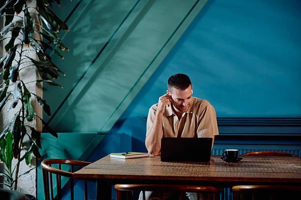 istock Young adult man working remotely at cafe using laptop 2246034484