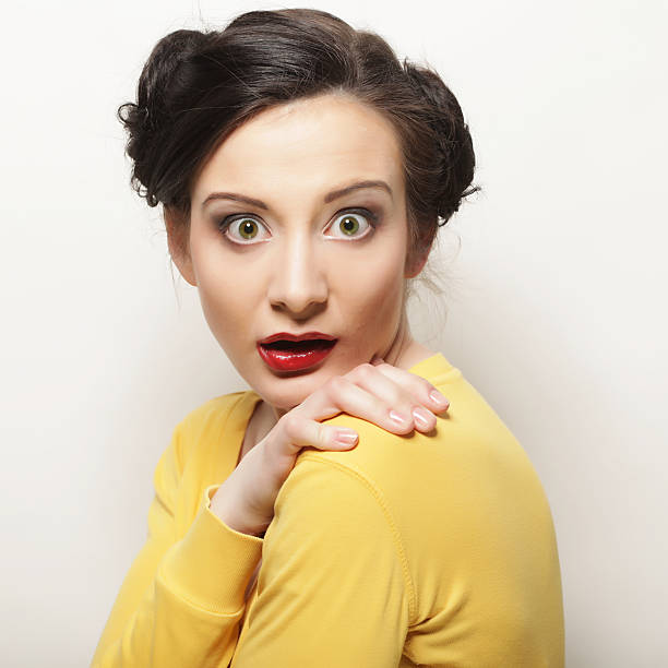 Portrait of real woman making a surprised face expression over gray background, studio shot
