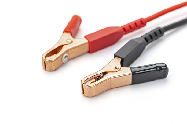 A pair of red and black alligator clips with jumper cables displayed on a white background, used for car battery jump starting and circuit maintenance, emphasizing electrical safety and durability.
