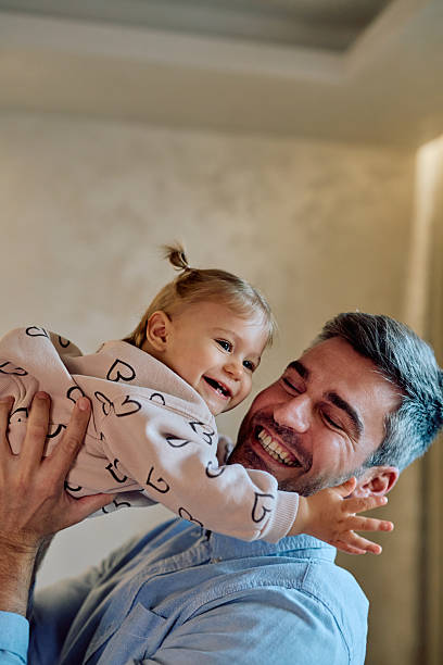 istock Happy father lifting up smiling baby daughter 2246036940