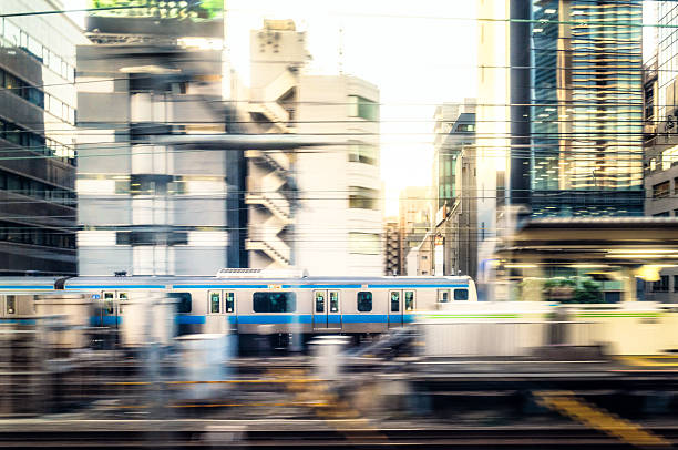 Motion blur with a panning image of a local train as it speeds past the buildings of downtown Tokyo.