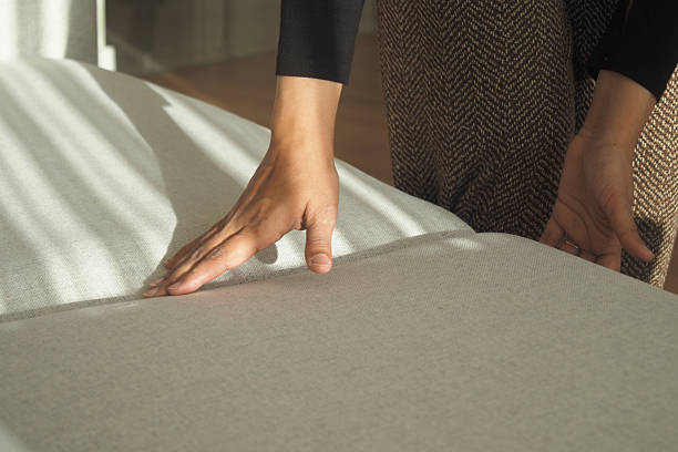 istock Person smoothing fabric on a couch in bright interior 2246040157