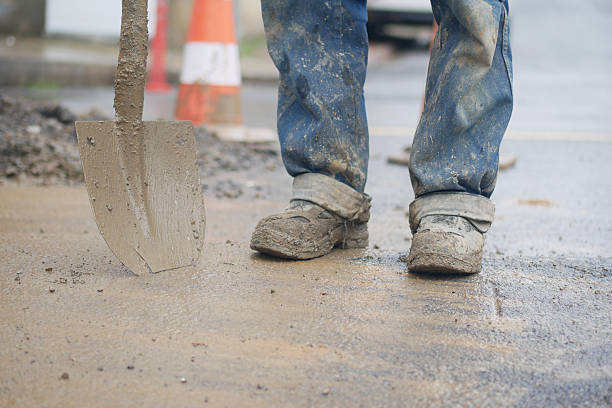 istock Construction worker digs in wet concrete during road repair 2246041109