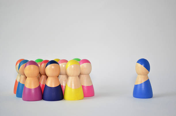 istock Solitary blue wooden figure standing apart from group 2246041403