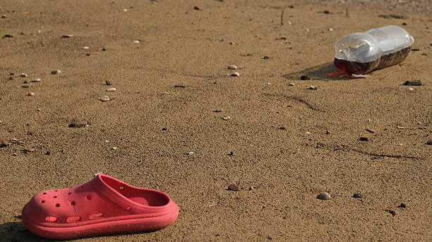 A red slipper and a plastic bottle on the sand