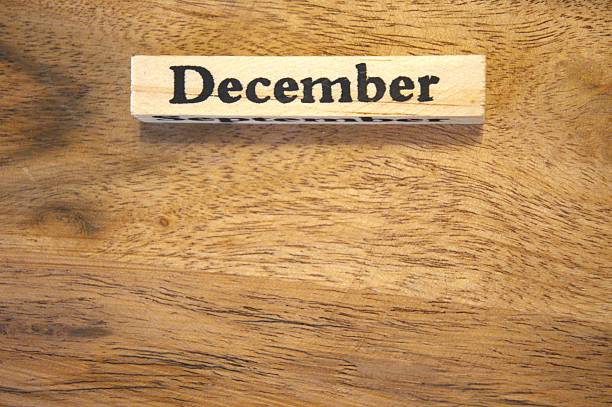 The word December displayed on a wooden cube with natural wooden background, close-up view in natural condition.