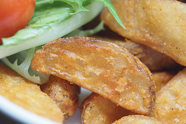 Freshly prepared crispy potato wedges served with salad and tomato.