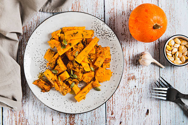Spicy salad with fried pumpkin, garlic and herbs on a plate on the table top view