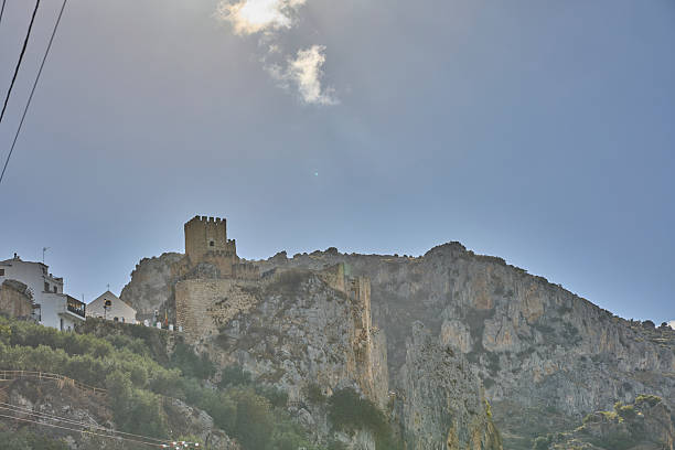 Medieval castle ruins and white houses built on a rocky mountain under a bright sky