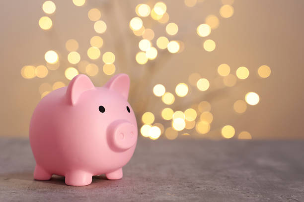 istock Pink piggy bank on grey table against blurred lights, space for text 2246053160