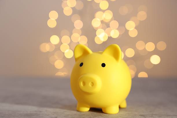 istock Yellow piggy bank on grey table against blurred lights, space for text 2246053184
