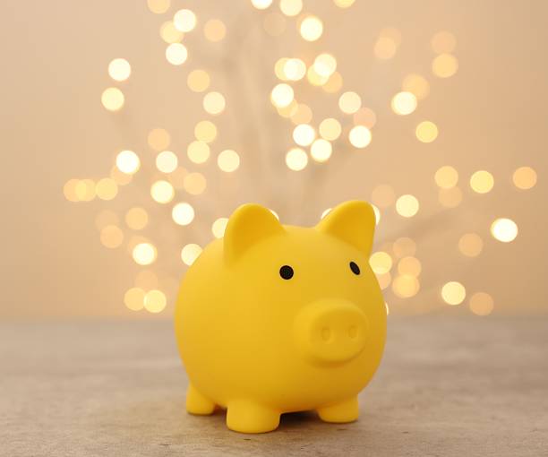 istock Yellow piggy bank on grey table against blurred lights, space for text 2246053195