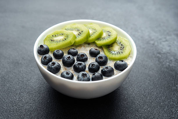 istock Oatmeal bowl with kiwi and blueberries with assorted fruit on black table 2246056603
