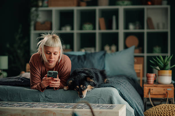 istock Woman and dog relaxing on bed using phone 2246058594