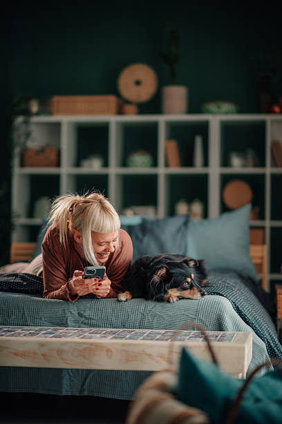 istock Woman with dog relaxing in bed using phone 2246058690
