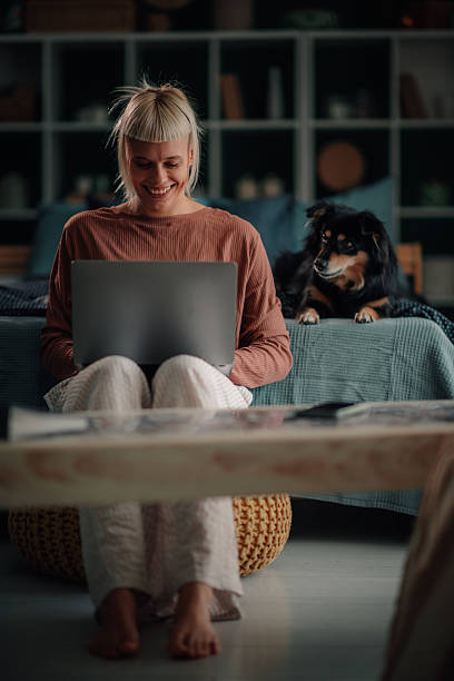 istock Young woman smiling, working on laptop with pet dog 2246058747