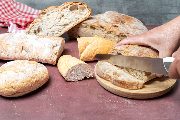 istock Hand slicing rustic bread loaf for fresh meal 2246059358