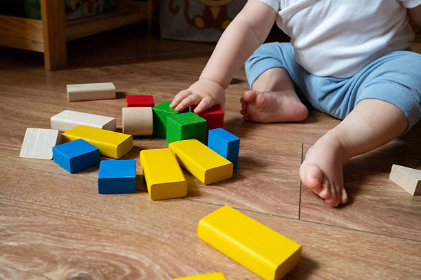 istock Baby Playing on Wood Floor with Colorful Blocks 2246060624