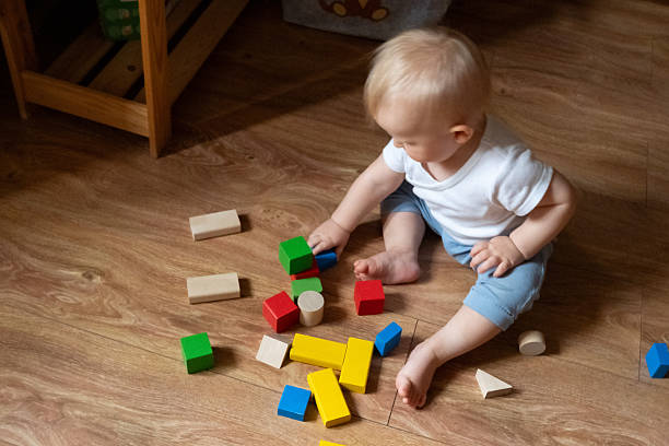 istock Child Stacking Colorful Blocks on Wooden Floor 2246060810