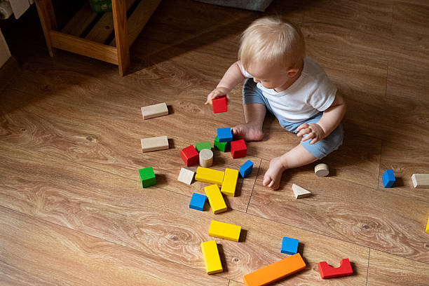 istock Child Stacking Colorful Blocks on Wooden Floor 2246060906