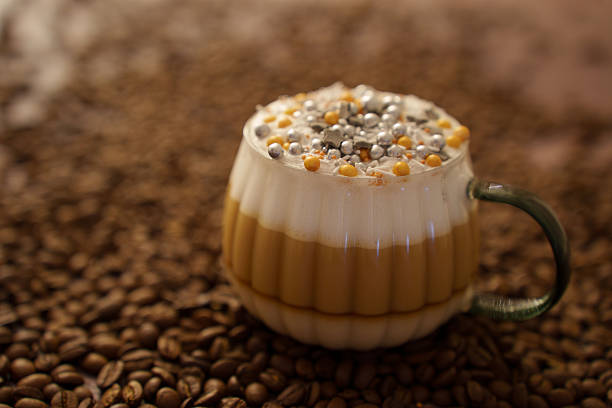aesthetic coffee drink with creamy foam and decorative metallic sprinkles served in a textured glass mug, set against a rich background of coffee beans conveying warmth and indulgence, ornate