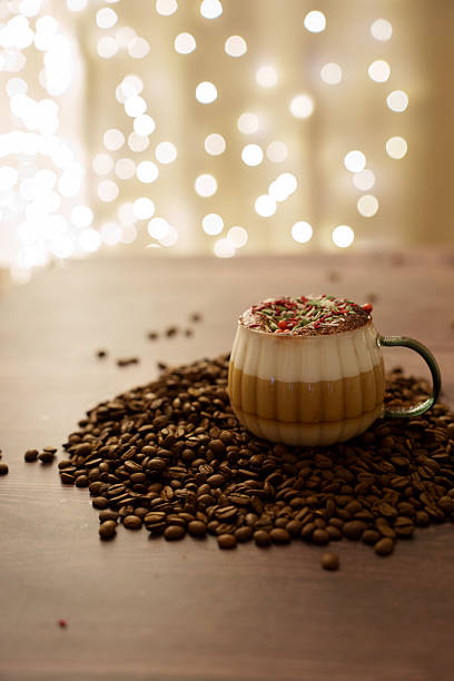 istock a cozy scene featuring a delicious layered coffee beverage adorned with festive sprinkles, surrounded by scattered coffee beans on a wooden surface, illuminated by soft, warm bokeh lights, focus 2246062455