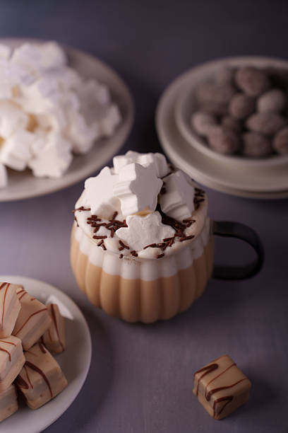 istock cozy setting featuring a creamy hot drink topped with star-shaped marshmallows and chocolate sprinkles, surrounded by plates of delicate sweets and chocolates creating a warm, inviting atmosphere 2246062492