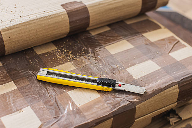 Utility knife. Cardboard box wrapped with tape