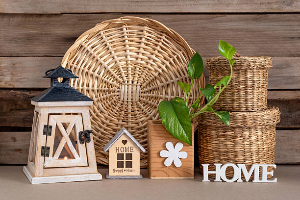 The letters of the word Home, a lantern, a house layout, baskets, and a decorative flower on a wooden background. Rustic home interior decoration. Sweet home.
