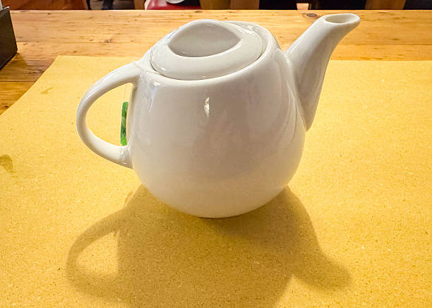 istock White ceramic teapot on wooden table with yellow placemat and shadow 2246063518