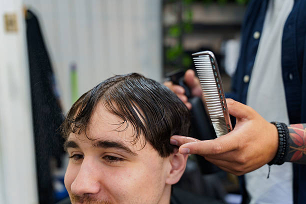 Customer receiving a haircut and wet hair treatment from a barber for styling