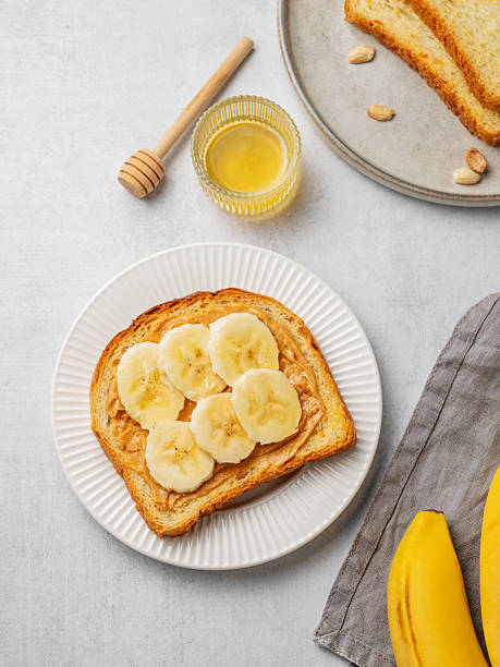 istock Peanut butter toast and banana in a white plate on a light background 2246064644