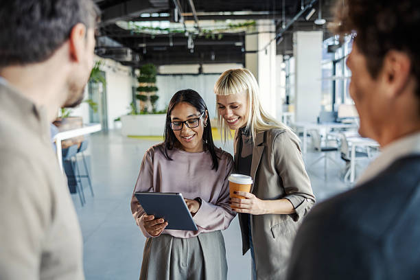 istock Businesswomen sharing ideas looking at tablet with colleagues 2246065514