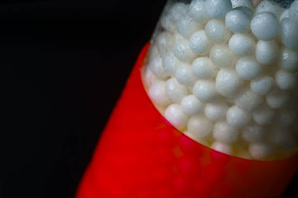 Macro shots of a red and white capsule filled with tiny white granules. The photos emphasize texture, transparency, and color contrast, symbolizing health, medicine, and pharmaceutical precision.