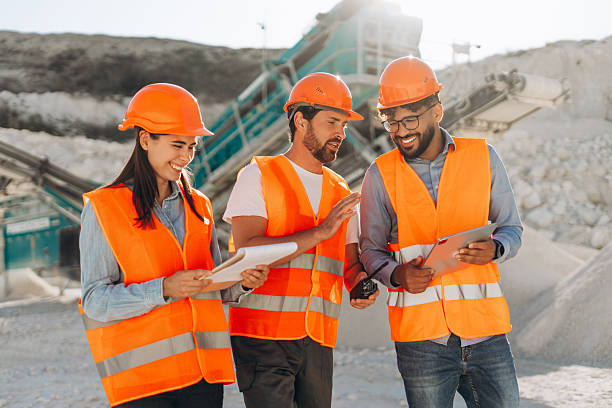 istock Happy workers in safety vests talking and smiling at quarry, using walkie talkie and documents 2246066149