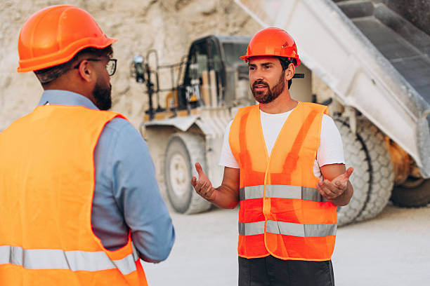 istock Two construction workers wearing orange safety vests and helmets at a quarry site 2246066281