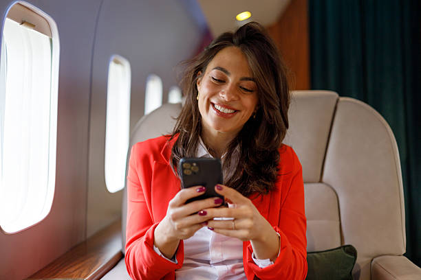 istock Successful woman smiling while using smartphone on private jet, enjoying business travel and luxury lifestyle 2246068964