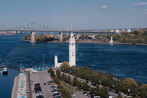 The iconic Clock Tower stands along the Saint Lawrence River at Montreal’s Old Port, with the green steel Jacques Cartier Bridge spanning the background. This historic waterfront area blends scenic views, maritime heritage, and vibrant seasonal activity.