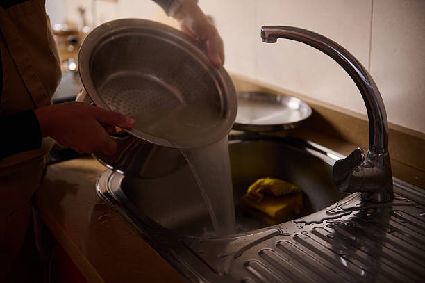istock Kitchen Sink Dishwashing Scene With Running Water And Hands Rinsing A Pot 2246072100