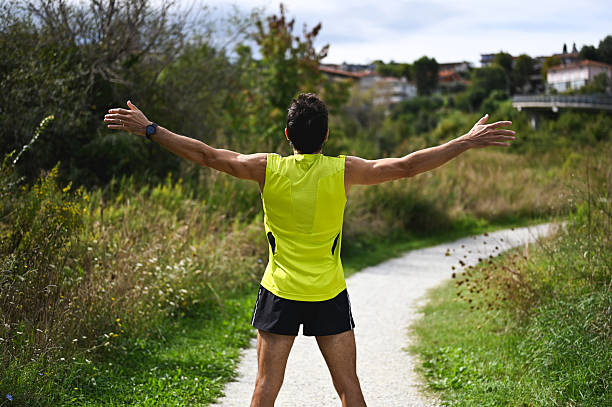 Man extending arms while standing on a path in nature, enjoying freedom