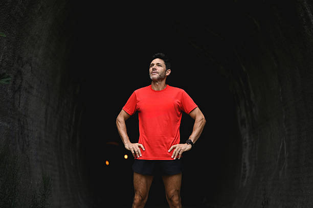 Man standing in a dark tunnel, hands on hips, looking up for inspiration